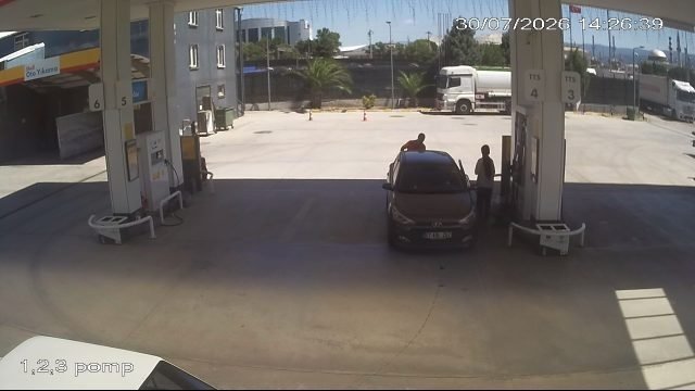 Attendant refuelling a car at a dispenser island, faces and plate redacted